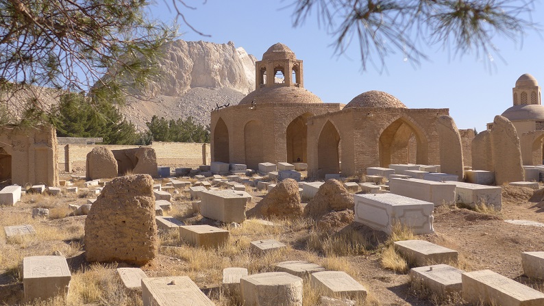 عکس سال ۲۰۱۵ از گورستان سِرَح بت آشر در پیربکران، با سنگ‌قبرها و بنای گنبددار آجری در دامنهٔ کوه.